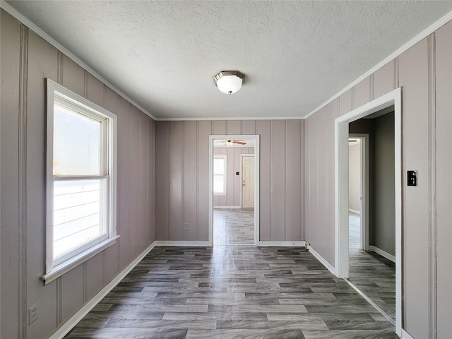 unfurnished room featuring dark wood-type flooring, plenty of natural light, a textured ceiling, and ornamental molding