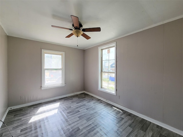 spare room with crown molding, plenty of natural light, and wood finished floors