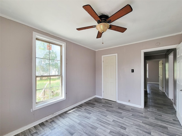 unfurnished bedroom with crown molding, wood finished floors, a ceiling fan, and baseboards