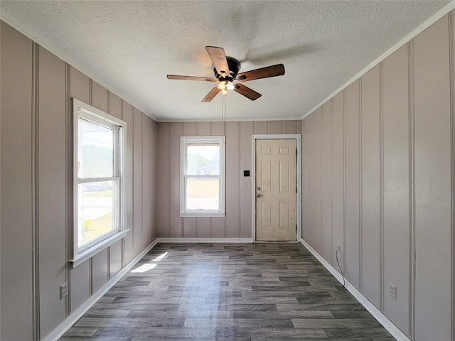 interior space featuring dark wood-style floors, a ceiling fan, ornamental molding, and a textured ceiling