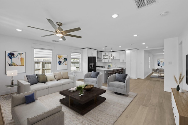 living area featuring baseboards, light wood-style flooring, visible vents, and recessed lighting