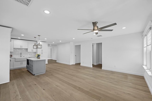 kitchen featuring open floor plan, a kitchen island, a sink, and visible vents