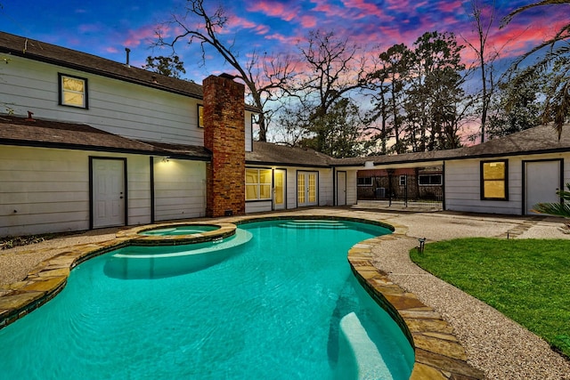 pool at dusk with a pool with connected hot tub and a patio