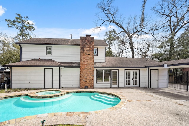 view of pool with a pool with connected hot tub, fence, a patio, and french doors