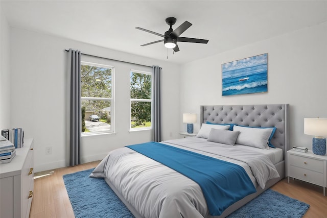 bedroom with light wood finished floors, a ceiling fan, and baseboards