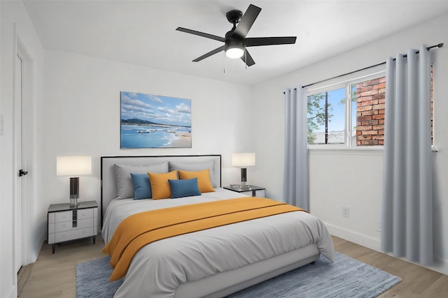 bedroom featuring light wood finished floors, a ceiling fan, and baseboards