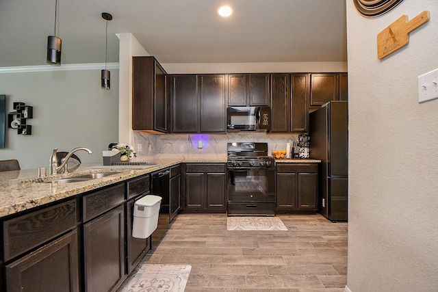 kitchen featuring decorative backsplash, light stone countertops, dark brown cabinets, black appliances, and a sink