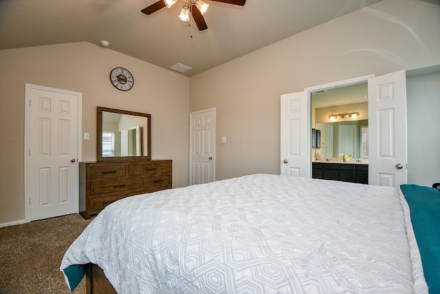 bedroom featuring visible vents, dark carpet, ensuite bathroom, vaulted ceiling, and ceiling fan