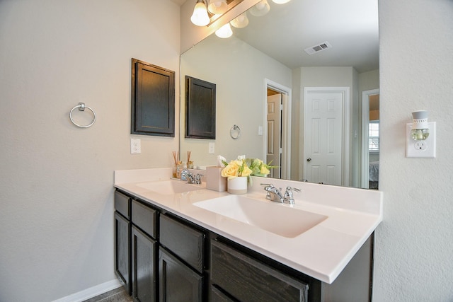 bathroom featuring baseboards, visible vents, a sink, and double vanity