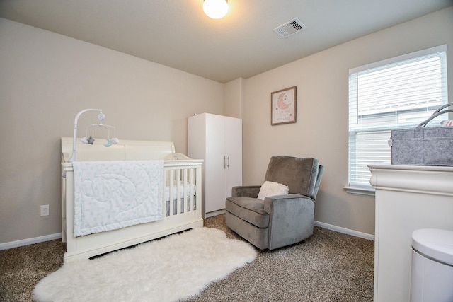 carpeted bedroom with baseboards, a nursery area, and visible vents
