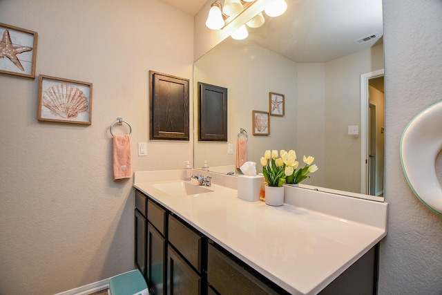 bathroom featuring a textured wall, vanity, and visible vents