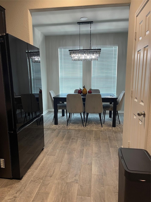 dining room with light wood finished floors and a notable chandelier