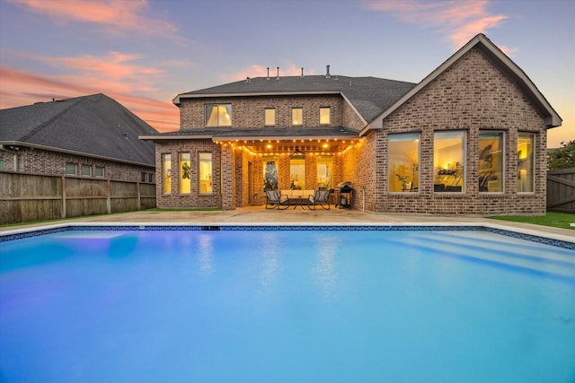 rear view of property featuring a fenced backyard, a fenced in pool, brick siding, ceiling fan, and a patio area