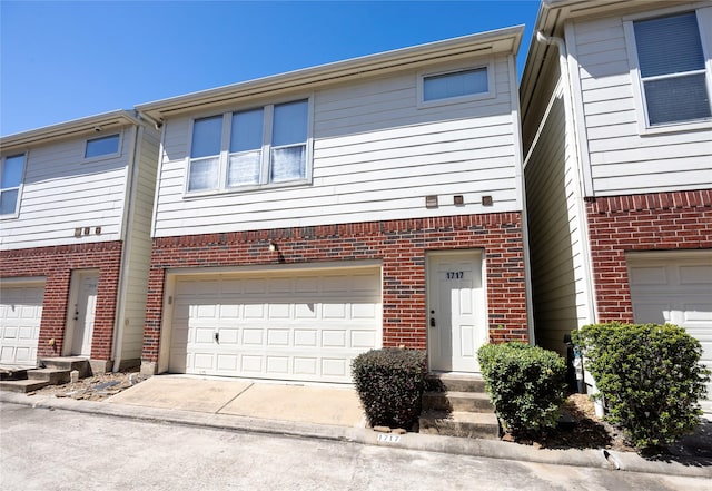 view of property featuring a garage, brick siding, driveway, and entry steps