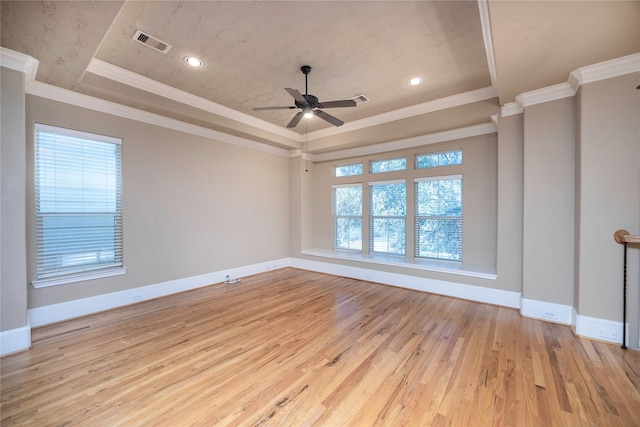 unfurnished room featuring visible vents, baseboards, a tray ceiling, ornamental molding, and wood finished floors