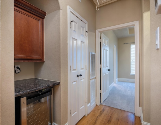 hallway with wine cooler, visible vents, light wood finished floors, and baseboards