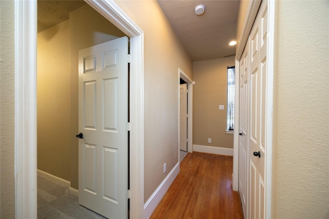 hallway featuring baseboards and wood finished floors