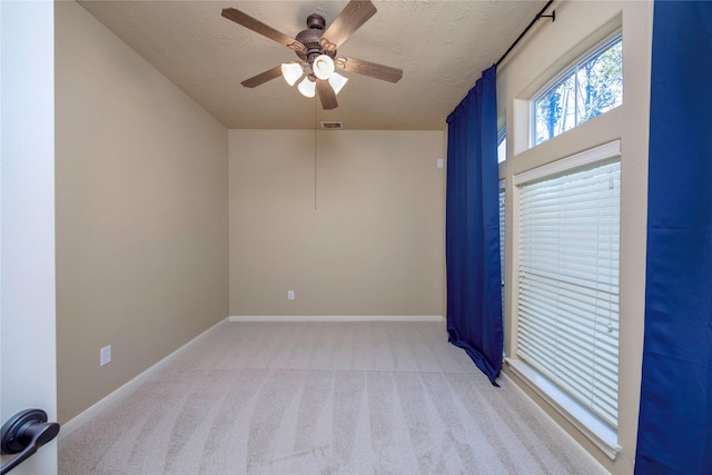 unfurnished room with visible vents, light carpet, a textured ceiling, baseboards, and ceiling fan