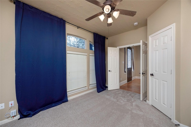 unfurnished bedroom with baseboards, ceiling fan, a textured ceiling, and carpet