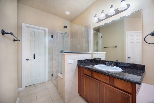 full bath featuring tile patterned flooring, a stall shower, vanity, and a textured ceiling