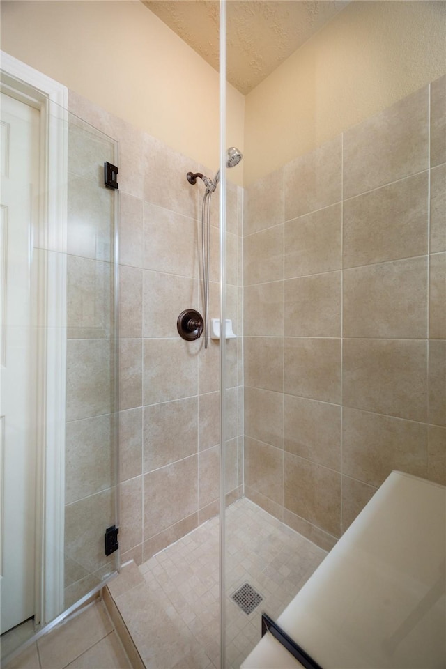 bathroom featuring a shower stall, tile patterned floors, and a textured ceiling