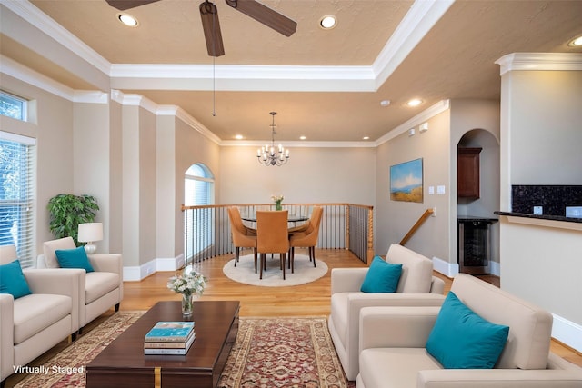 living room featuring light wood-style flooring, recessed lighting, ornamental molding, wine cooler, and a raised ceiling