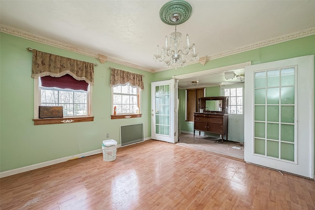 unfurnished dining area with ornamental molding, a notable chandelier, baseboards, and wood finished floors