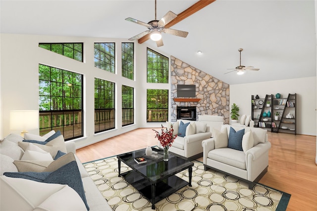 living room featuring a ceiling fan, high vaulted ceiling, wood finished floors, and a stone fireplace