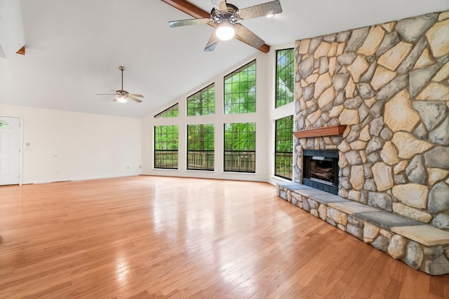 unfurnished living room featuring a fireplace, wood-type flooring, a ceiling fan, high vaulted ceiling, and beamed ceiling