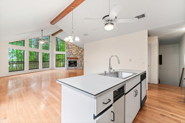 kitchen featuring beamed ceiling, a fireplace, a sink, and a healthy amount of sunlight