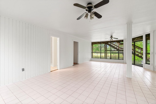 spare room with a ceiling fan, floor to ceiling windows, a healthy amount of sunlight, and light tile patterned floors