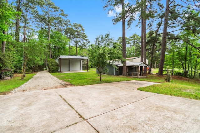 view of front of home featuring an outbuilding, driveway, a standing seam roof, and a front yard