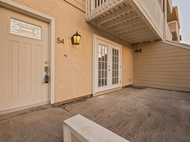 view of exterior entry featuring french doors and stucco siding