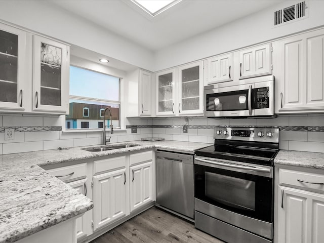 kitchen with tasteful backsplash, visible vents, appliances with stainless steel finishes, white cabinets, and a sink