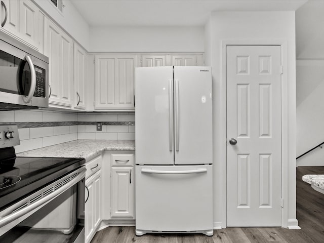 kitchen with tasteful backsplash, appliances with stainless steel finishes, white cabinetry, and light wood-style floors