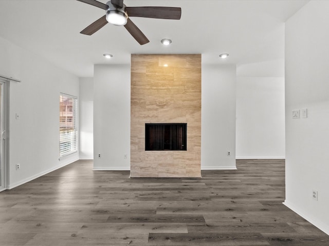 unfurnished living room with ceiling fan, a fireplace, baseboards, and wood finished floors