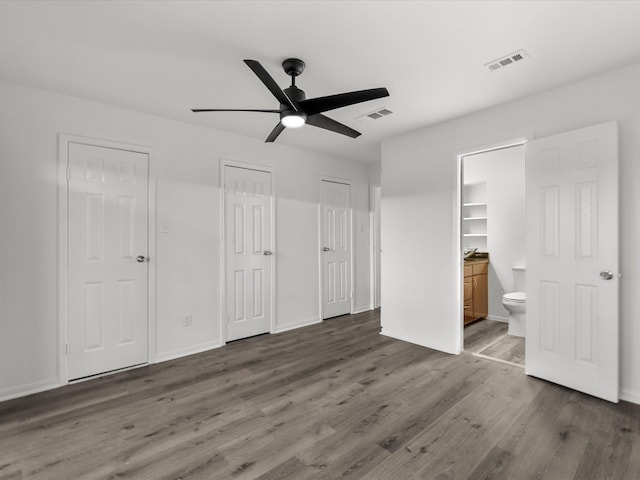 unfurnished bedroom with connected bathroom, visible vents, baseboards, and wood finished floors