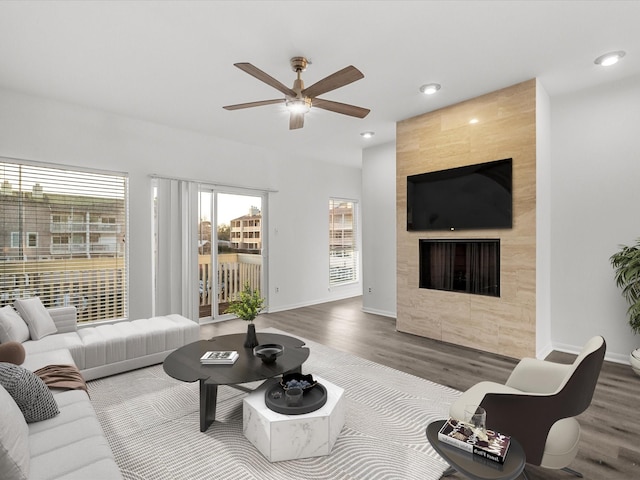 living area featuring a ceiling fan, wood finished floors, a fireplace, and baseboards