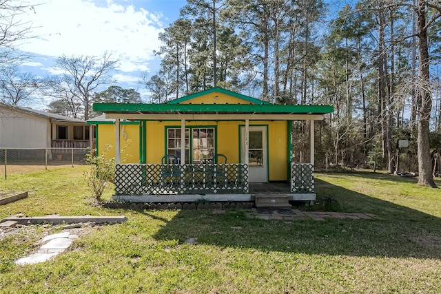 view of front of house featuring covered porch, fence, and a front lawn