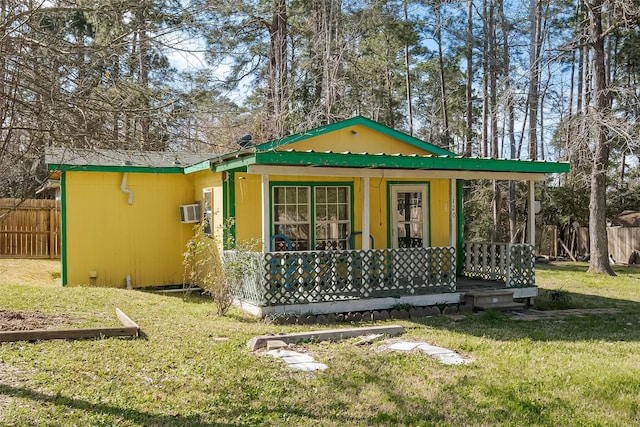 view of front of home featuring a porch, a wall unit AC, a front yard, and fence