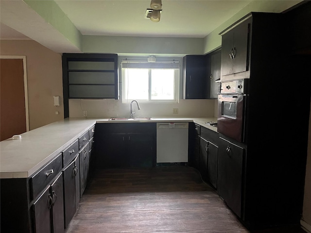 kitchen with wall oven, dishwasher, dark cabinets, a peninsula, and light countertops