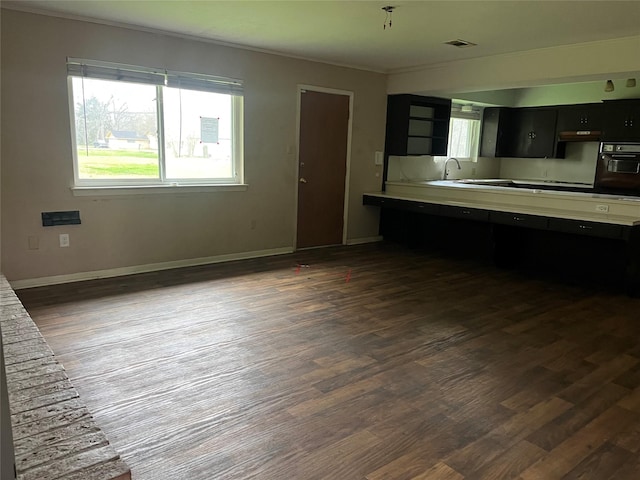 kitchen featuring oven, dark cabinets, dark wood-style flooring, visible vents, and baseboards