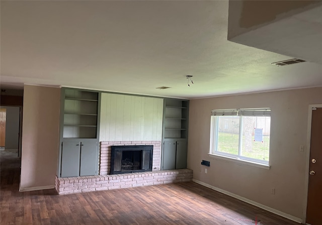 unfurnished living room featuring a brick fireplace, baseboards, visible vents, and wood finished floors