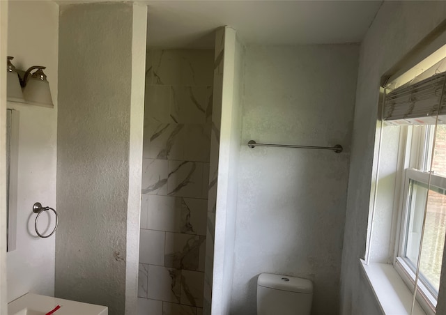 bathroom featuring toilet, a shower, and a textured wall