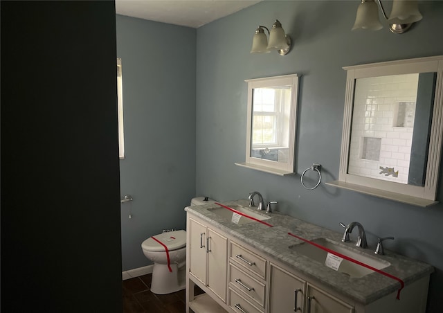 bathroom featuring baseboards, a sink, toilet, and double vanity