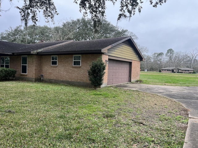 view of side of property featuring a garage, brick siding, and a yard