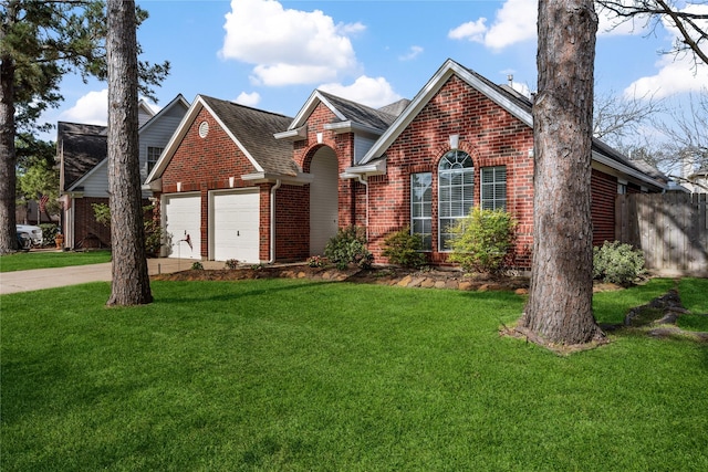 traditional-style home featuring driveway, a front lawn, fence, a garage, and brick siding