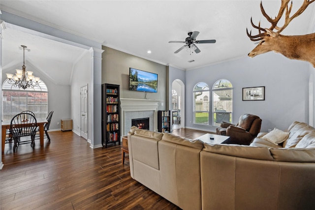 living room featuring baseboards, a fireplace, ornamental molding, dark wood-type flooring, and ceiling fan with notable chandelier