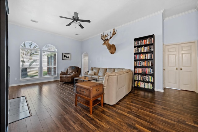 living room featuring dark wood finished floors, visible vents, arched walkways, and ornamental molding