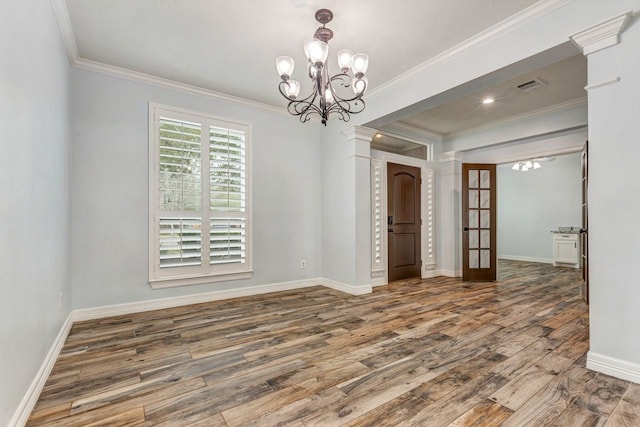 unfurnished dining area with crown molding, a notable chandelier, visible vents, wood finished floors, and baseboards